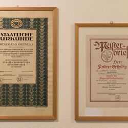 Die Meisterbriefe von André Gründig und seinem Vater gerahmt und an der Wand hängend.