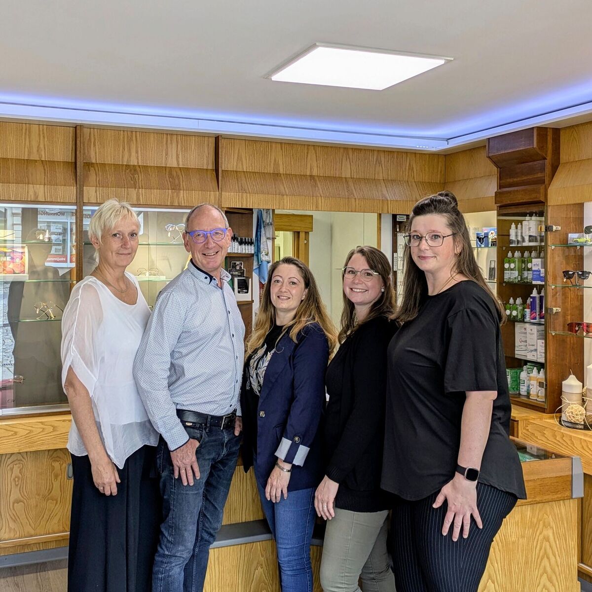 Gruppenbild des Team im Ladengeschäft. Im Hintergrund sind Präsentationsregale mit Brillengestellen.