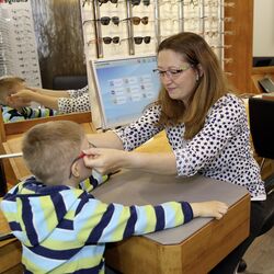 Beratungsgespräch: Die Optikerin passt einem Kind das Brillengestell an.
